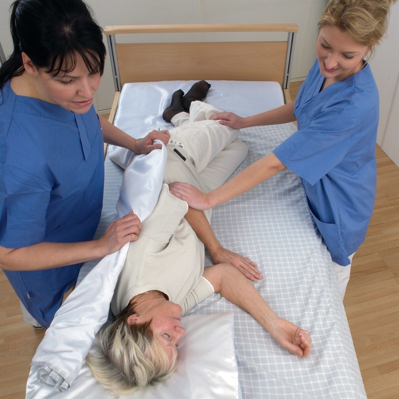 Carers using a sliding sheet to transfer a patient